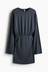 Vestido corto de punto elástico color gris oscuro, con escote redondo, mangas largas, cuerpo holgado y pollera entallada con frunces laterales.
