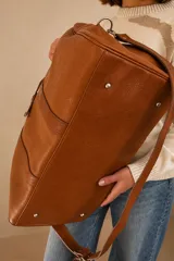 Bolso tipo Duffle color suela, confeccionado 100% en cuero vacuno, con asas de mano y correa larga ajustable y desmontable.