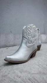 Botas texanas de caña corta en color plateado metalizado, con diseño de costuras decorativas en el lateral y taco cuadrado de madera.