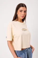 Remera coral cropped, de manga corta, con estampa trasera colorida de un perro surfeando y el texto "Rusty County Surf Club".