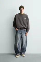 Sudadera gris oscuro de corte relaxed fit, cuello redondo y manga larga, con estampa en contraste en el pecho y acabados en rib.