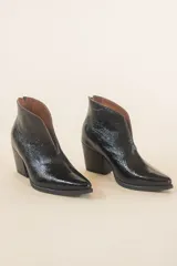 Botinetas negras de cuero charol, con corte en V en el empeine y taco geométrico.