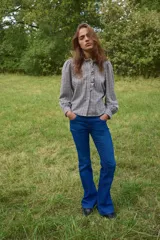 Jean de tiro bajo con diseño de cinco bolsillos, cierre frontal con botón y corte ajustado en la parte superior con piernas acampanadas.