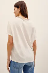 Remera de lino y viscosa color blanco, de corte holgado, manga corta y escote en V con detalle de aplicación brillante.
