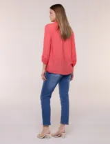 Blusa celeste de silueta suelta y textura liviana, con escote en V, cuello mao y cierre frontal de botones. Cuenta con alforzas verticales en el pecho y mangas tres cuartos con puños elastizados y detalle de galón calado.