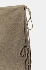 Pantalón de punto fino color beige, de corte recto y holgado, con cintura elástica y una falda pareo superpuesta con nudo lateral.