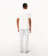 Pijama largo para hombre confeccionado en algodón, compuesto por una remera de manga corta blanca con cuello redondo celeste y estampa frontal de Snoopy, y un pantalón largo celeste con estampado general de Snoopy y cintura elástica.