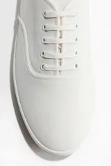 Championes de lona de algodón en color blanco, con cordones, suela de goma y diseño clásico.