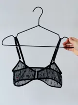 Top negro de microtul con estampado de pequeñas flores, breteles finos regulables y cierre frontal.