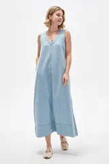 Vestido largo de jean celeste, sin mangas, con escote en V profundo, corte holgado y costuras visibles a contratono.