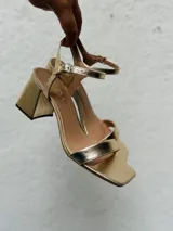 Sandalias negras de tacón bajo y ancho, con punta cuadrada, talón abierto y tira fina ajustable al tobillo.