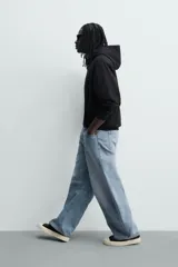 Jeans de denim de algodón color gris con efecto lavado, de corte relaxed barrel fit y tiro medio. Presenta diseño amplio con pinzas en las rodillas y costuras curvas, cierre frontal con botones y cinco bolsillos tradicionales.