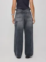 Jean de corte baggy y tiro medio, confeccionado en denim de algodón en tono azul claro con efecto lavado. Presenta diseño de cinco bolsillos, cierre frontal con botón y cremallera, y pernera ancha.