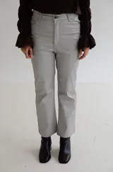 Pantalón cropped de tiro medio con acabado engomado, corte recto y bolsillos laterales. Presenta cierre frontal con botón y costuras a tono.