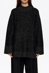 Sweater de punto negro con efecto tweed o neps en color dorado/amarillo claro, cuello alto tipo caja y mangas largas. Corte recto y holgado.