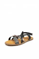 Sandalia plana Bettina modelo BT308, con tiras cruzadas en el empeine de colores negro, dorado y con brillos plateados, y tira ajustable al tobillo.