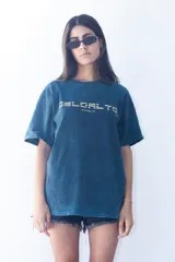 Remera de corte oversize con efecto de lavado ácido en color azul petróleo. Presenta un estampado gráfico frontal en color amarillo con tipografía moderna y la inscripción 'Montevideo, UY'.