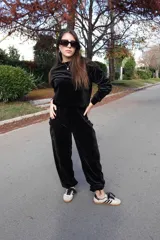 Conjunto de dos piezas confeccionado en tejido plush aterciopelado color negro. Incluye un buzo de corte cropped con cuello redondo y mangas largas, y un pantalón estilo cargo de silueta holgada con bolsillos laterales funcionales y puños ajustables en los tobillos.