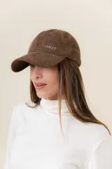 Gorra de diseño clásico con visera curva, confeccionada en material símil gamuza color bordó. Presenta un logo metálico con la palabra Peach en la parte frontal y cuenta con un sistema de ajuste posterior.