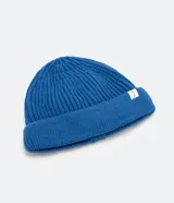 Gorro tipo fisherman de tejido acrílico con textura acanalada, diseño corto y etiqueta pequeña con logo en el frente.