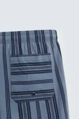Bañador de hombre de largo medio, color azul claro con rayas verticales en azul oscuro. Posee cintura elástica ajustable con cordón, bolsillos laterales y un bolsillo trasero de plastrón.