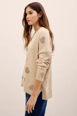 Sweater tejido de punto color beige con diseño holgado, cuello redondo, manga larga y aplicación de corazones formados con tachas brillantes en contraste.