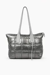Cartera tipo shopper de diseño acolchado con costuras cuadradas, en color gris metalizado. Cuenta con doble asa larga para llevar al hombro y cierre superior.