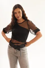 Blusa negra transparente de plumetí con frunces en los hombros y mangas 3/4.