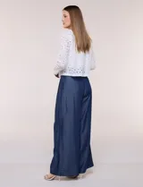 Chaqueta corta de calce recto en tejido broderie blanco, con diseño calado de perforaciones geométricas y florales, escote redondo, frente abierto y mangas largas.