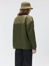 Campera tejido grueso y abrigado color verde militar, con forro de nylon interno, cuello estilo camisa en color negro y cierre frontal con botones. Cuenta con cuatro bolsillos delanteros con apliques en distintos tonos y texturas, y un parche bordado circular en el bolsillo superior izquierdo.