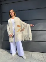 Pashmina color crema tejida en lana merino con apliques de cuero en tonos marrones y flecos en los bordes.