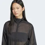 Campera deportiva Adidas Adicolor Sheer, color negro, de corte holgado y tejido transparente. Cuenta con cierre frontal, cuello alto, puños y dobladillo acanalados.