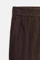Pantalón de lino marrón oscuro, de corte barrel con pernera holgada que se estrecha hacia el tobillo, cintura elástica y bolsillos delanteros.
