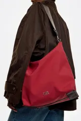 Bolso bandolera de tamaño pequeño confeccionado en nylon, con estructura blanda y cierre de cremallera. Cuenta con asa larga regulable de tejido y logo de la marca aplicado en la parte inferior frontal.