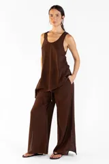 Pantalón ancho de color marrón, con pretina elástica, bolsillos laterales y aberturas en los bajos. Confeccionado en tejido fluido.
