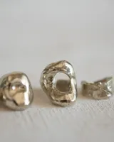 Anillo de metal macizo color plateado con forma orgánica irregular y superficie texturizada.