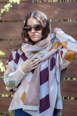 Bufanda tejida de algodón con diseño de rombos en tonos beige, bordó, rosa y mostaza. Presenta una etiqueta de cuero sintético con logo en uno de sus extremos.