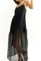 Vestido negro de lino con breteles finos y corte irregular. Presenta una falda larga de encaje floral.