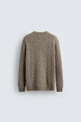 Jersey de punto con diseño de trenzas verticales, cuello redondo y manga larga. Presenta un ajuste regular y acabados en rib en cuello, puños y ruedo.