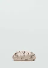 Bolso de mano tipo clutch, confeccionado en piel caprina color beige, con diseño fruncido y adornado con pequeñas esferas metálicas plateadas distribuidas por toda la superficie.