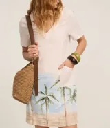 Vestido corto de viscosa y lino, corte recto, con escote en V, mangas cortas y estampado de palmeras en el ruedo.