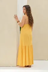 Vestido largo mostaza de lino, con tirantes finos, escote en V con abertura frontal y detalle de volado en el ruedo.
