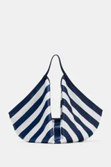 Maxi bolsa de hombro con diseño de rayas horizontales en azul marino y blanco, asa superior integrada y cierre con botón imantado.
