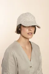 Gorra con visera confeccionada en lana fina sin teñir, con un sutil patrón de tejido en espiga.