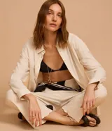 Pantalón recto de cintura alta, color beige, confeccionado en viscolino con detalle de textura perforada con diseño de palmeras en el bajo. Cuenta con elástico en la parte posterior de la cintura y cierre frontal tradicional.