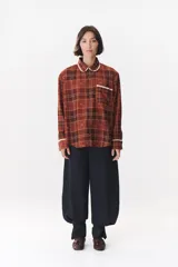 Camisa de corte holgado en color bordó con estampado de cuadros y monograma. Presenta cuello redondo con borde de puntilla, bolsillo frontal con detalle de puntilla, cierre frontal con botones y puños con terminación en puntilla.