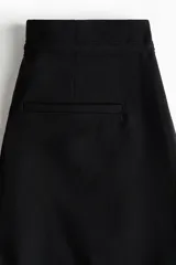 Pantalón de tiro alto con piernas amplias, pinzas frontales y raya marcada. Cuenta con cierre oculto, cordón ajustable en la cintura, bolsillos laterales discretos y bolsillos traseros insertados.