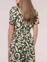 Enterito verde oscuro con estampado floral y abstracto en tono beige, de corte suelto y caída fluida. Presenta escote en V, mangas cortas, cintura elastizada con faja fruncida y pantalón crop de pierna ancha con bolsillos laterales.