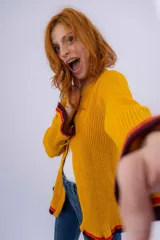 Saco de lana merino color mostaza, tejido a punto con detalle de volados en ruedo y puños. Tiene dos cierres frontales hechos en crochet a mano.