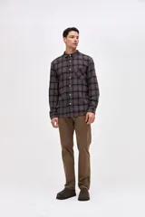 Camisa de corte regular fit, confeccionada en tela de algodón con diseño de cuadros en tonos marrones y negros. Presenta cuello clásico, cierre frontal con botones personalizados y un bolsillo en el pecho con el logo de la marca bordado.